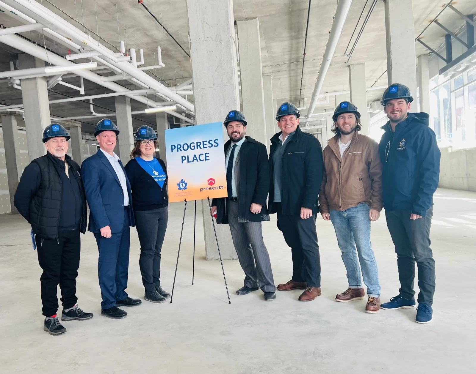 people from Prescott group, Lindsay Construction and the Halifax chapter of the Canadian Progress Club stand together in a large partially renovated room, celebrating the future home of Prescott group